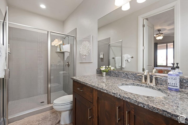 Full bathroom with a shower stall, toilet, ceiling fan, and vanity