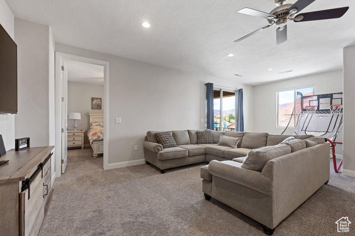Living room featuring light carpet, ceiling fan, baseboards, and recessed lighting