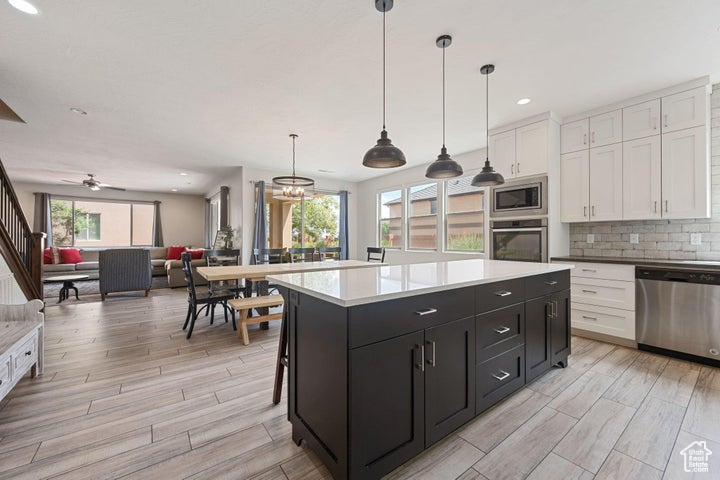 Kitchen featuring appliances with stainless steel finishes, white cabinets, open floor plan, dark cabinetry, and light wood-style floors