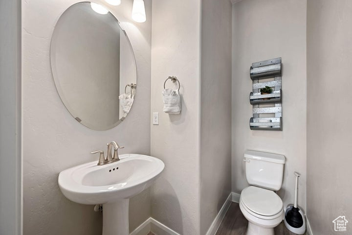 Bathroom featuring toilet, baseboards, and wood finished floors