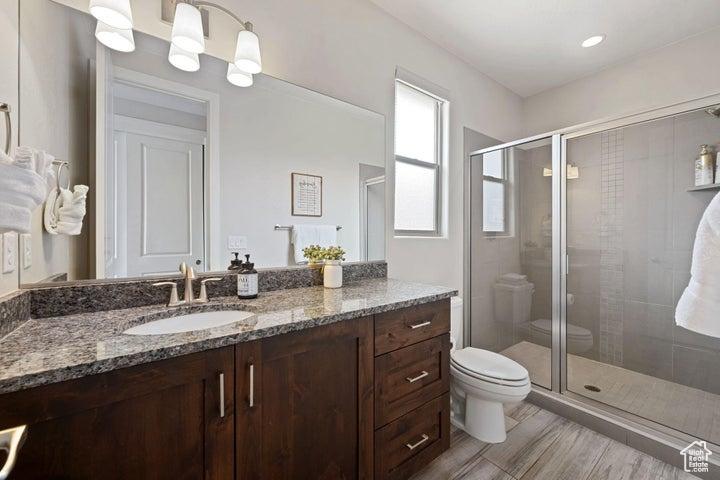 Bathroom featuring toilet, a shower stall, vanity, and wood finished floors