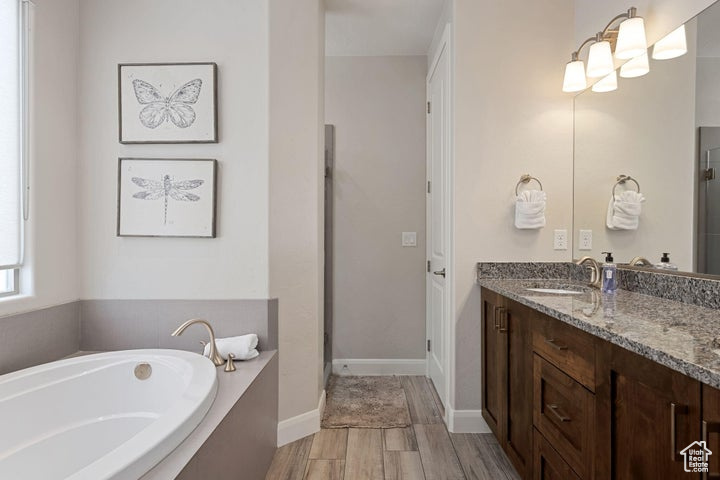 Full bath featuring vanity, a garden tub, wood finished floors, and a stall shower