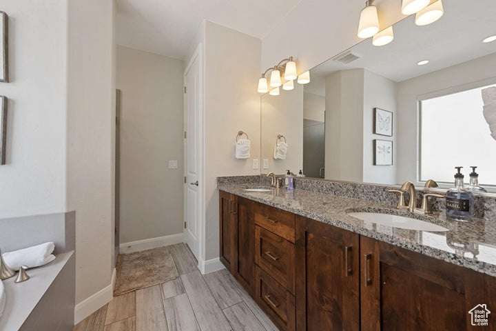 Full bath featuring double vanity, baseboards, and wood finished floors
