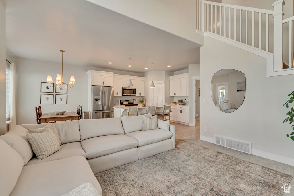Living area featuring a chandelier, recessed lighting, baseboards, and light colored carpet