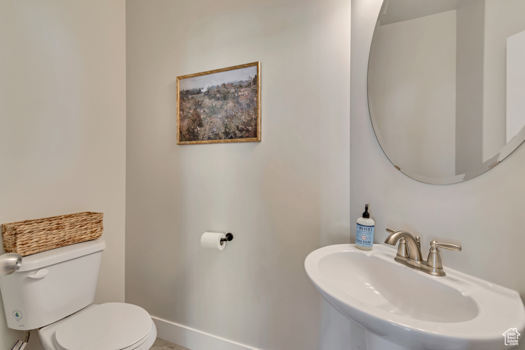 Bathroom featuring a sink, toilet, and baseboards