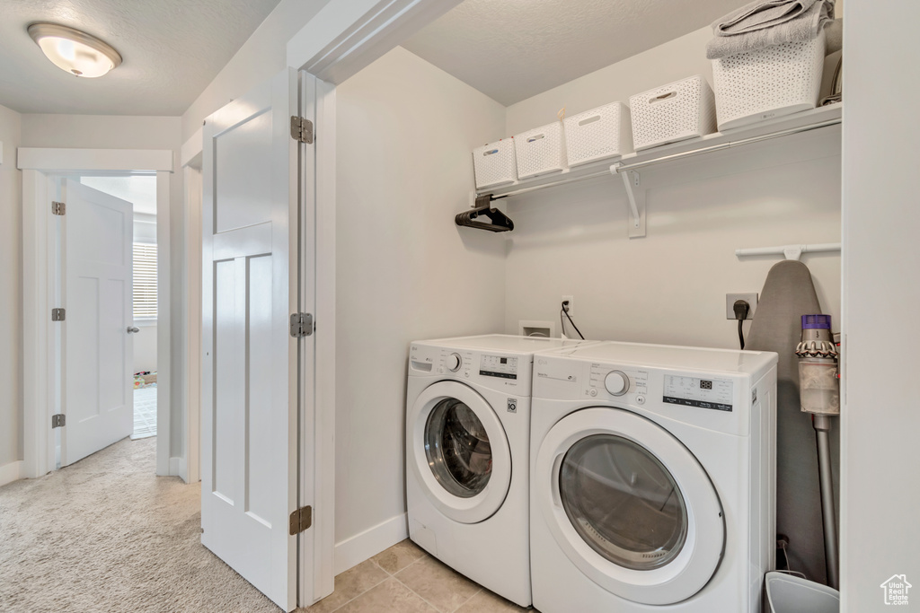 Washroom featuring washer and clothes dryer, baseboards, and light colored carpet