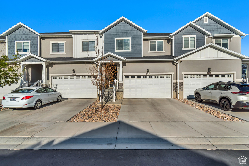 Townhome / multi-family property with a garage, driveway, board and batten siding, and stucco siding