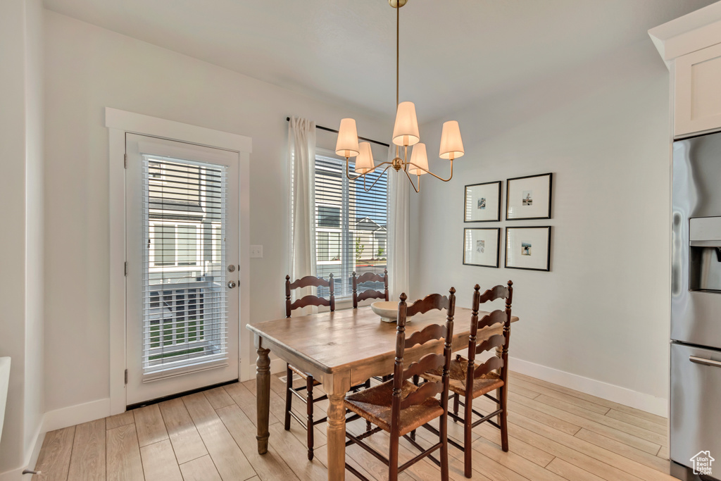 Dining room with light wood-style flooring, baseboards, and a chandelier