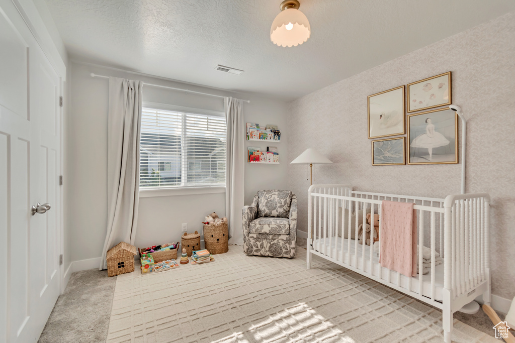 Bedroom featuring carpet flooring, a crib, and baseboards