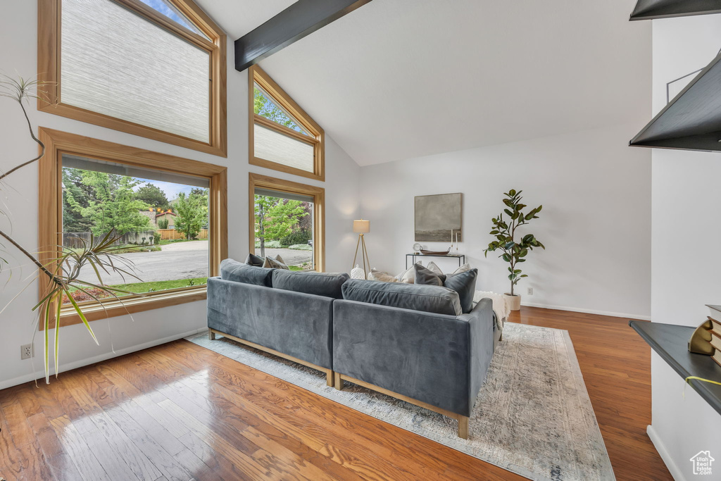 Living area featuring high vaulted ceiling, beam ceiling, wood finished floors, and baseboards
