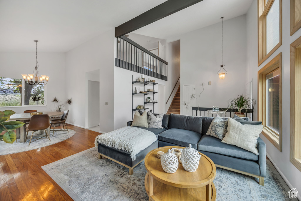 Living room featuring high vaulted ceiling, stairs, a chandelier, wood finished floors, and baseboards