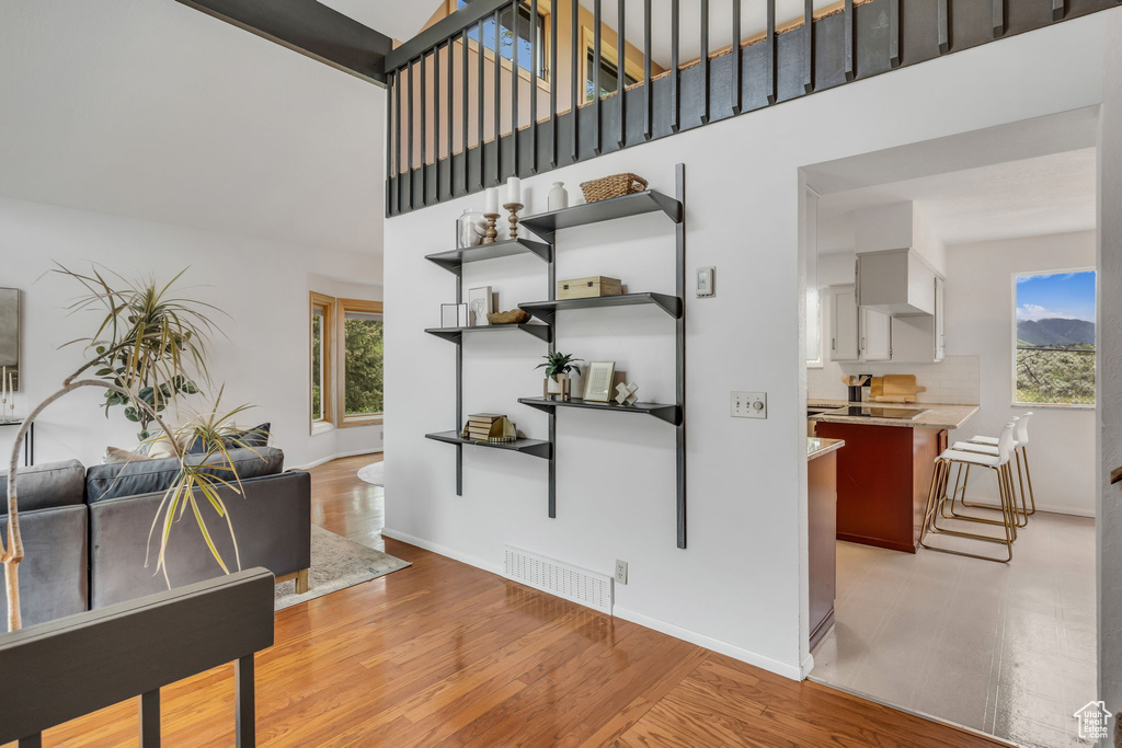 Interior space featuring a towering ceiling, baseboards, and light wood-style flooring