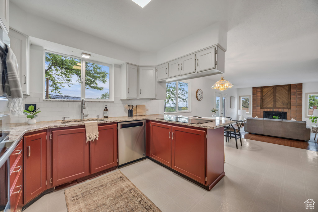 Kitchen with dishwasher, black electric stovetop, a brick fireplace, tasteful backsplash, and open floor plan