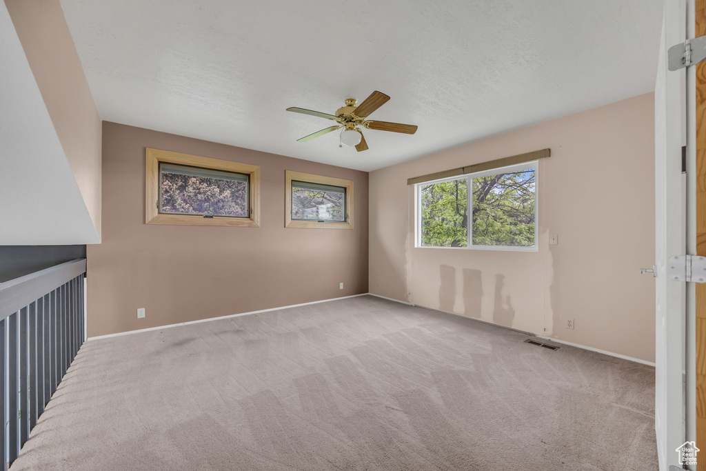Carpeted spare room with ceiling fan and baseboards
