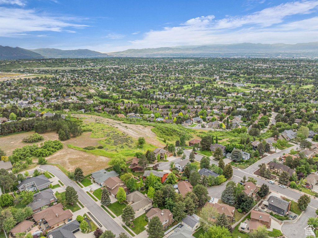 Aerial view of property and surrounding area featuring a mountainous background and nearby suburban area