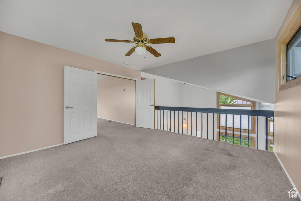 Carpeted empty room with a ceiling fan and baseboards