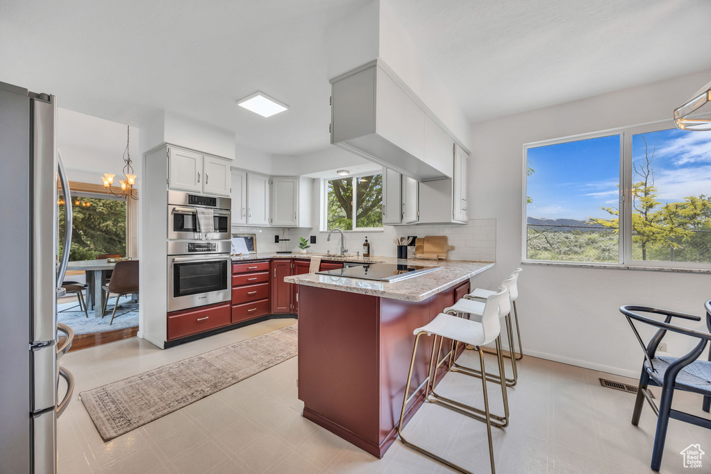 Kitchen featuring appliances with stainless steel finishes, a peninsula, backsplash, and healthy amount of natural light