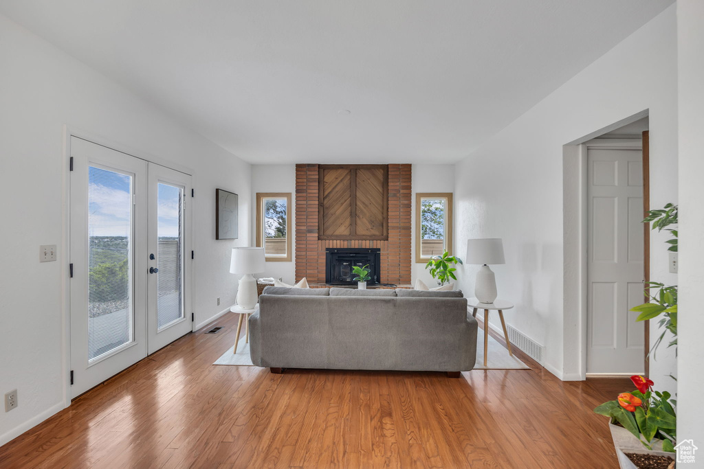 Living room featuring light wood-style flooring, baseboards, and a brick fireplace