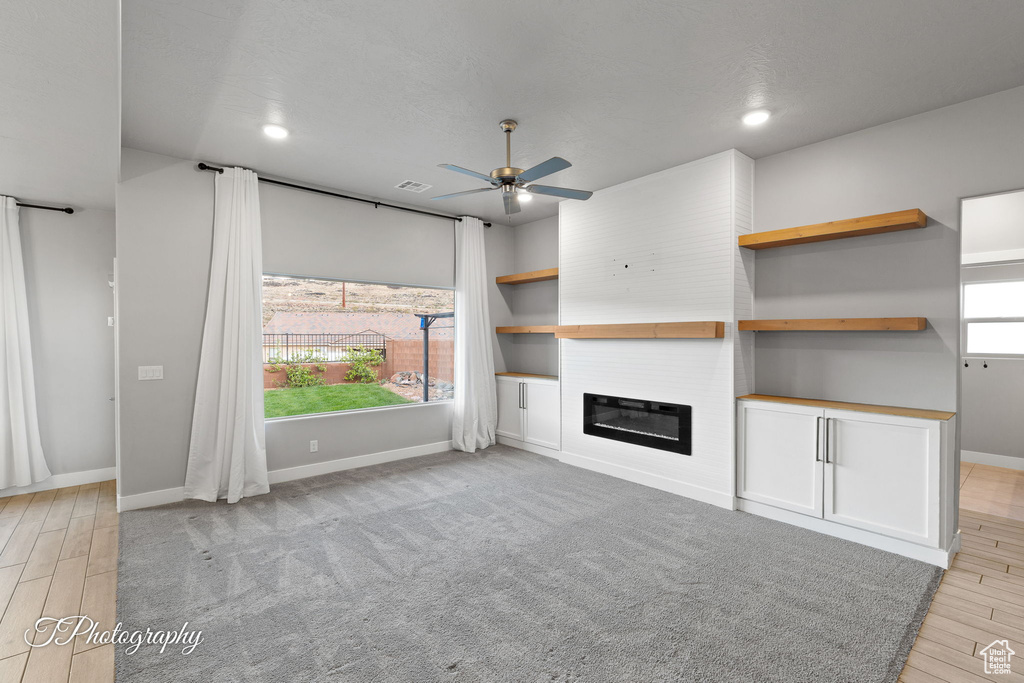 Unfurnished living room with a ceiling fan, baseboards, a large fireplace, light wood-style floors, and recessed lighting