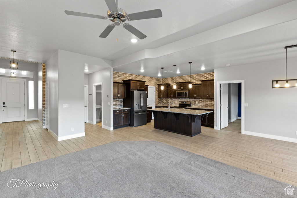 Kitchen with stainless steel appliances, open floor plan, dark brown cabinetry, and recessed lighting