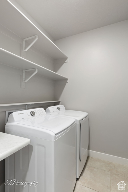 Washroom with washer and dryer, baseboards, and light tile patterned floors