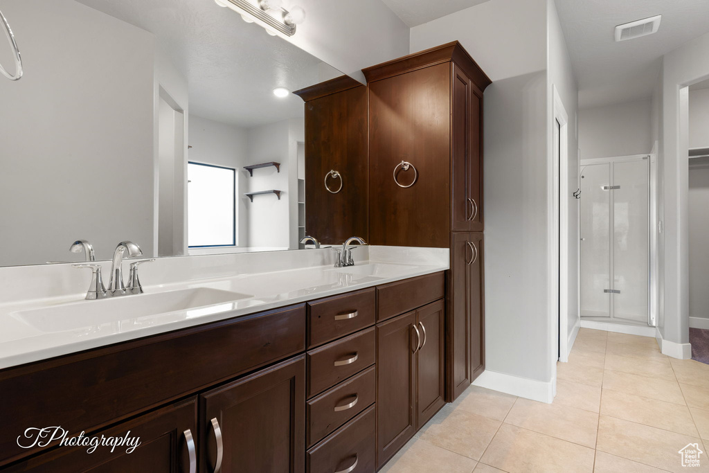 Full bathroom with tile patterned floors, a shower stall, double vanity, and baseboards