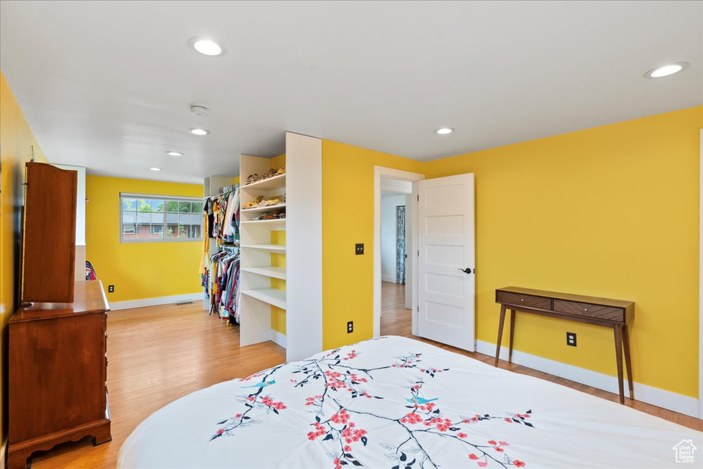 Bedroom featuring light wood-type flooring, baseboards, recessed lighting, a spacious closet, and a closet