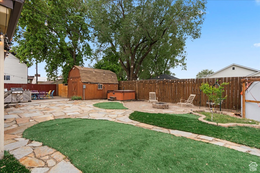 View of yard with a hot tub, a fire pit, a patio area, a shed, and an outbuilding