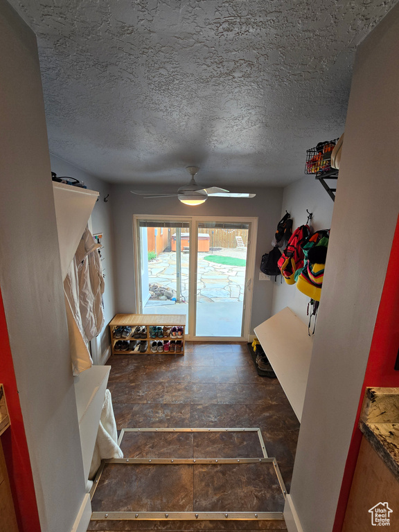 Staircase featuring a ceiling fan and a textured ceiling