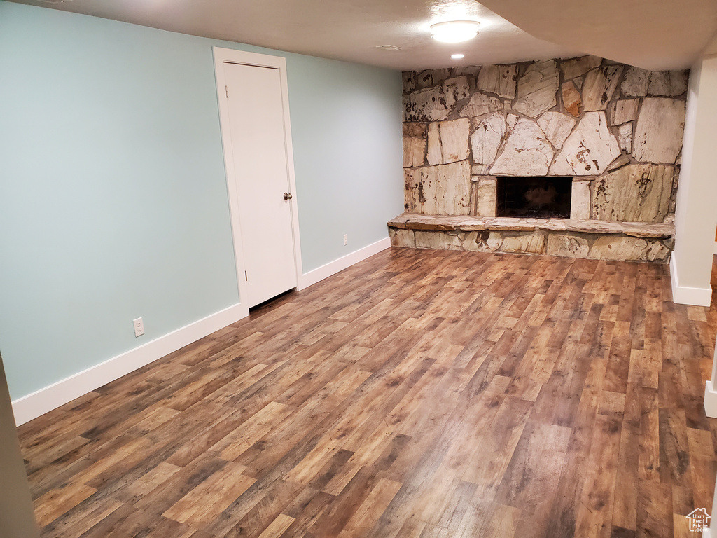 Unfurnished living room featuring wood finished floors, a fireplace, and baseboards