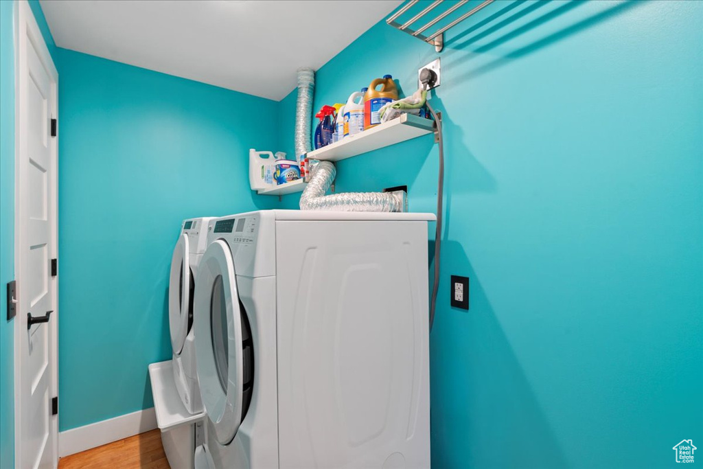 Laundry room featuring washer and dryer, wood finished floors, and baseboards