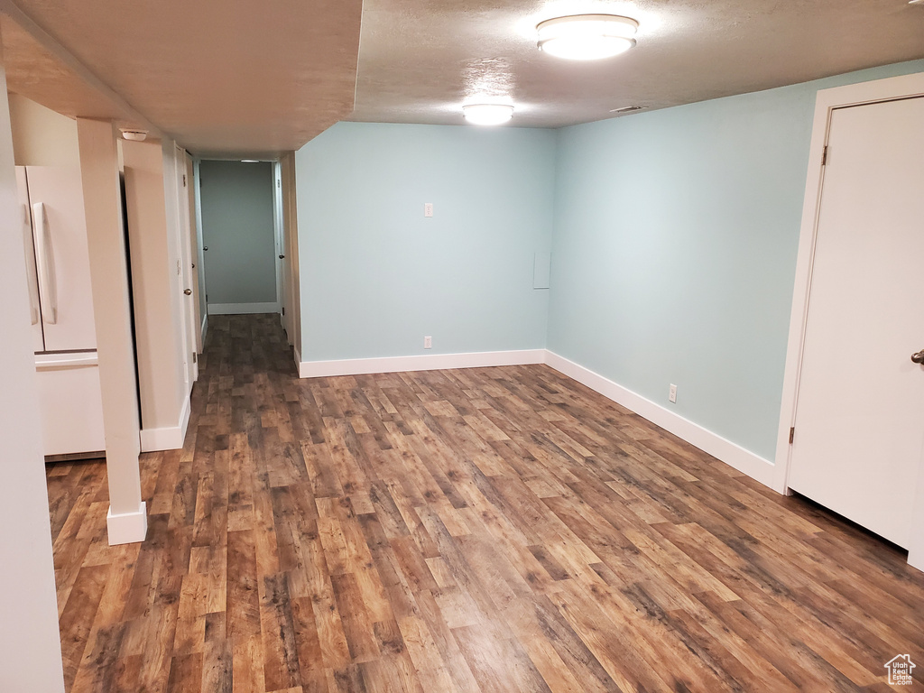 Finished basement featuring wood finished floors, freestanding refrigerator, and baseboards