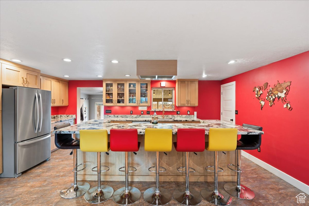 Kitchen with freestanding refrigerator, recessed lighting, a kitchen breakfast bar, a center island, and glass insert cabinets