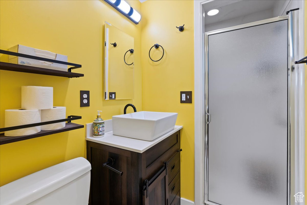 Bathroom featuring a shower stall, vanity, and toilet