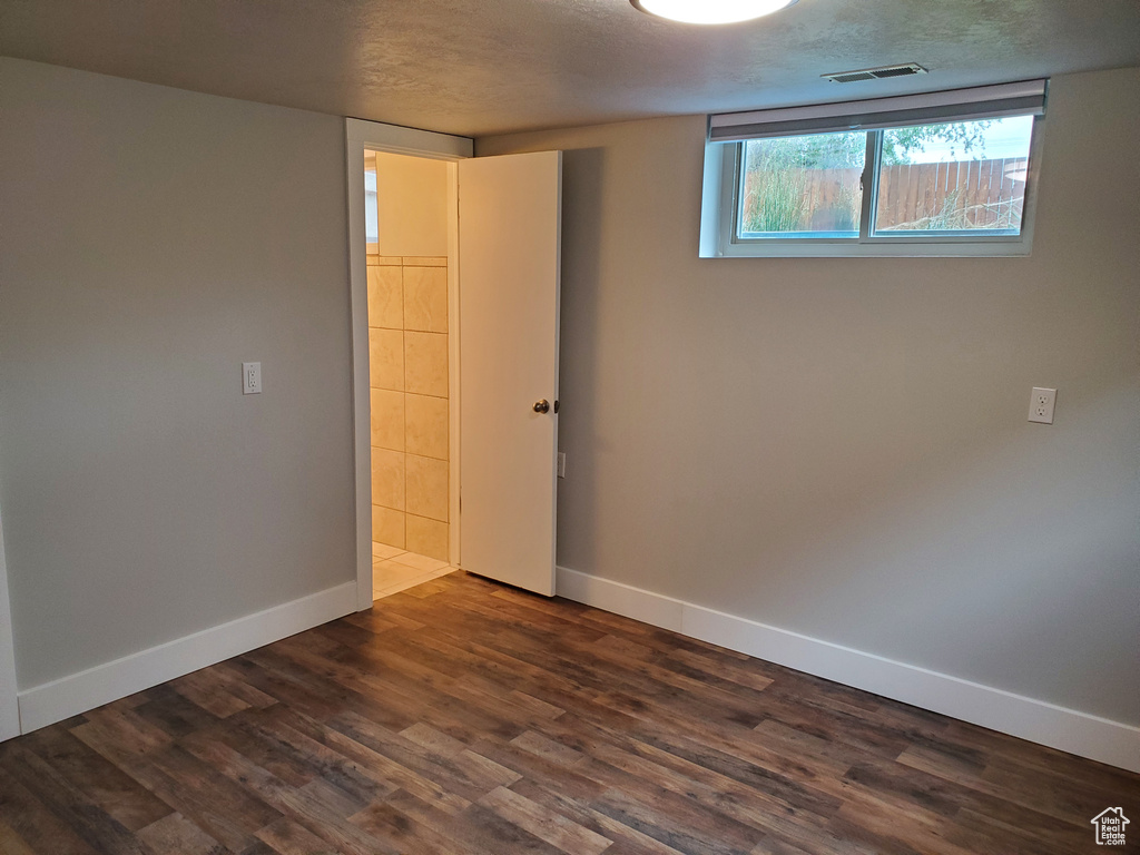 Unfurnished room featuring baseboards, dark wood-style floors, and a textured ceiling
