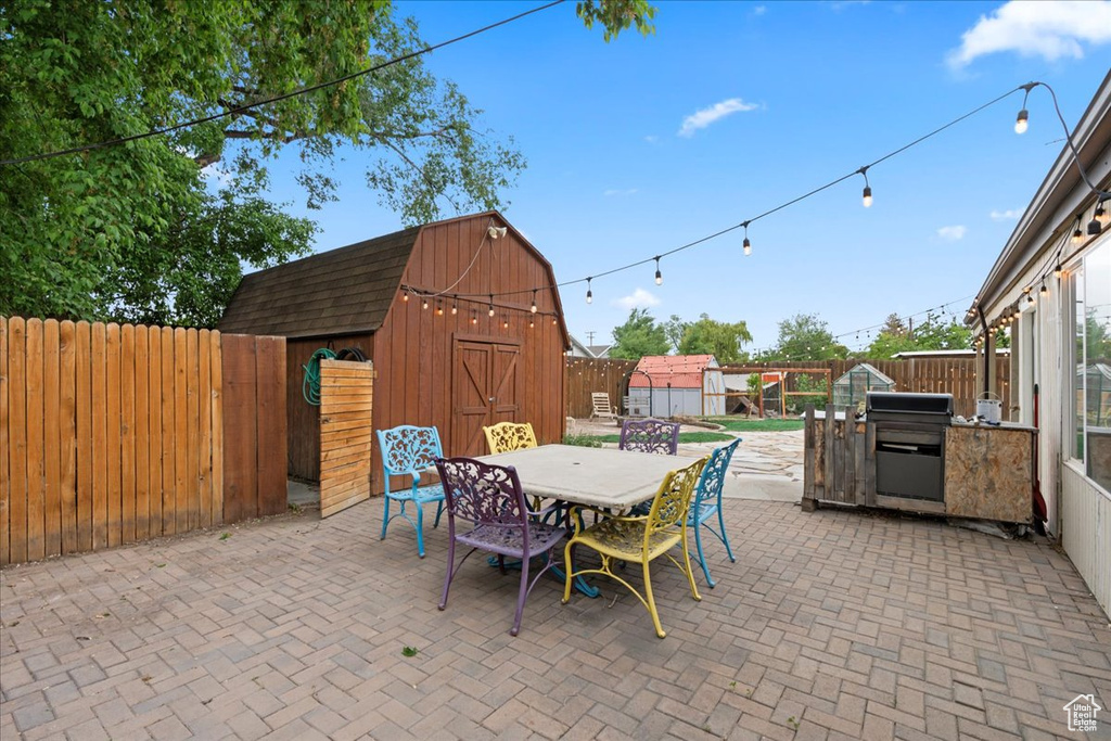 View of patio featuring an outdoor structure, outdoor dining area, a storage shed, and a fenced backyard