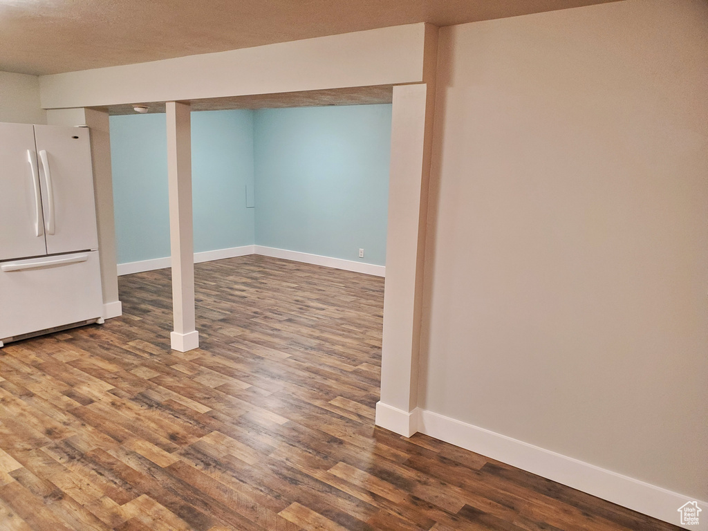 Finished basement with freestanding refrigerator, wood finished floors, and baseboards
