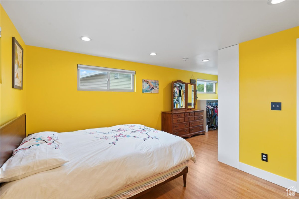 Bedroom with wood finished floors, recessed lighting, a spacious closet, and baseboards