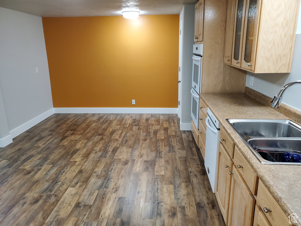 Kitchen featuring a sink, white appliances, dark wood finished floors, and light brown cabinets