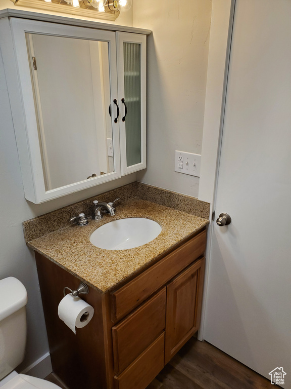 Half bath with toilet, vanity, and wood finished floors