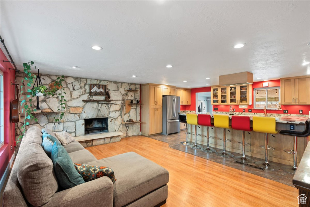 Living area with light wood-style flooring, bar area, recessed lighting, and a fireplace