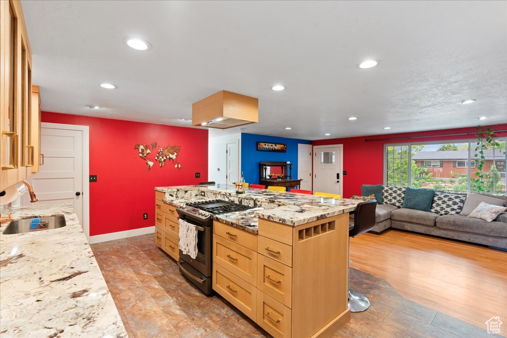 Kitchen with stainless steel gas range, a sink, recessed lighting, open floor plan, and light brown cabinetry