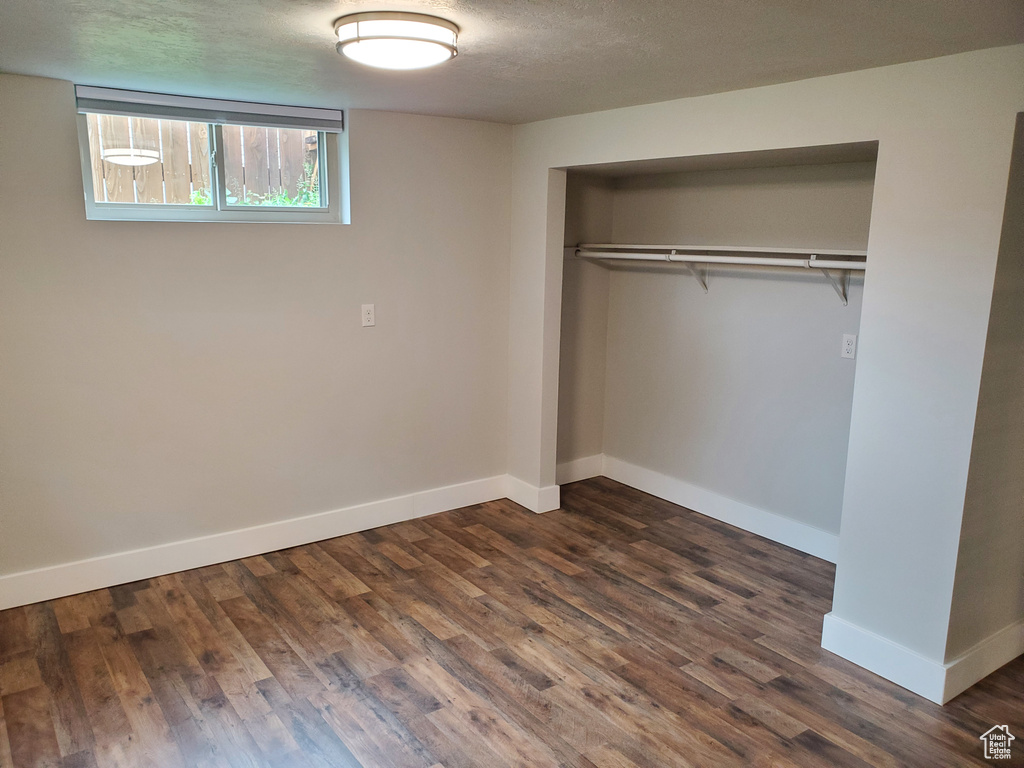 Unfurnished bedroom featuring baseboards, a closet, dark wood finished floors, and a textured ceiling