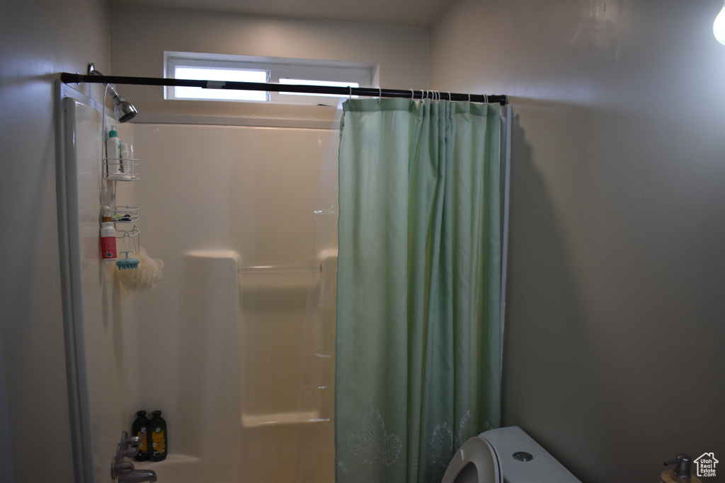 Bathroom featuring toilet and shower / bath combo with shower curtain