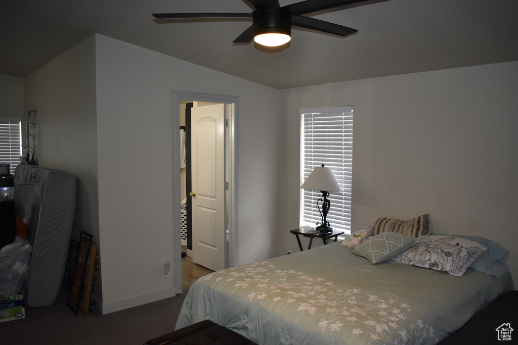 Carpeted bedroom with baseboards, vaulted ceiling, and ceiling fan