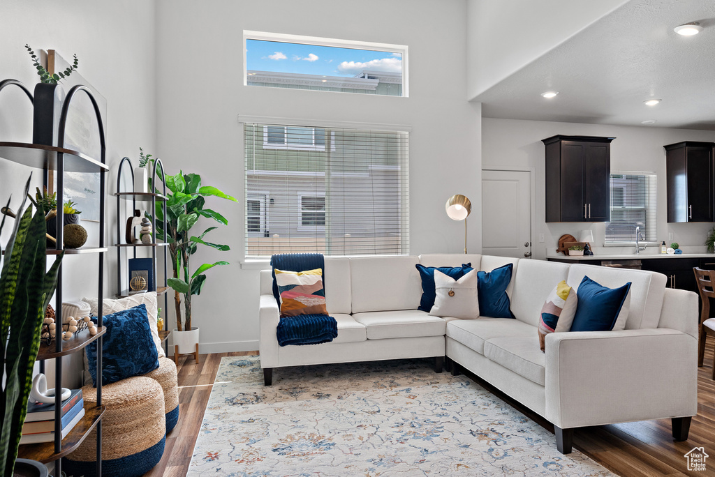 Living area featuring light wood-style flooring, healthy amount of natural light, a towering ceiling, recessed lighting, and baseboards