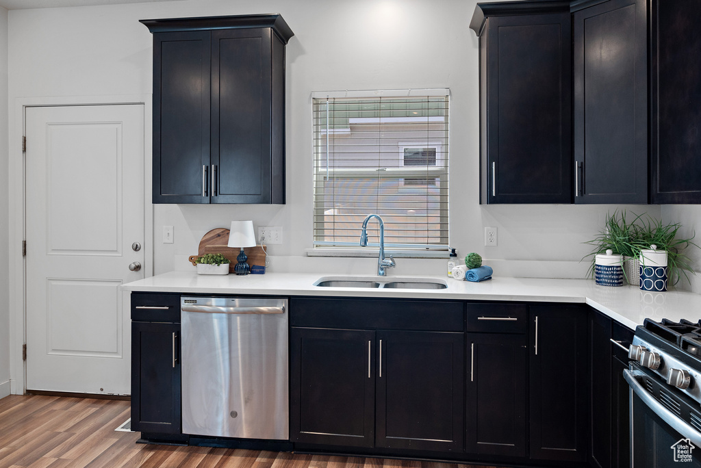 Kitchen with stainless steel dishwasher, a sink, gas range oven, and dark cabinetry