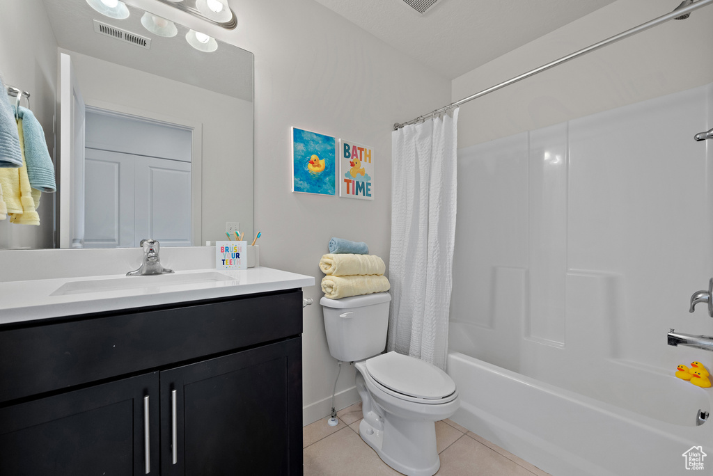 Full bath featuring tile patterned flooring, toilet, vanity, shower / tub combo with curtain, and baseboards