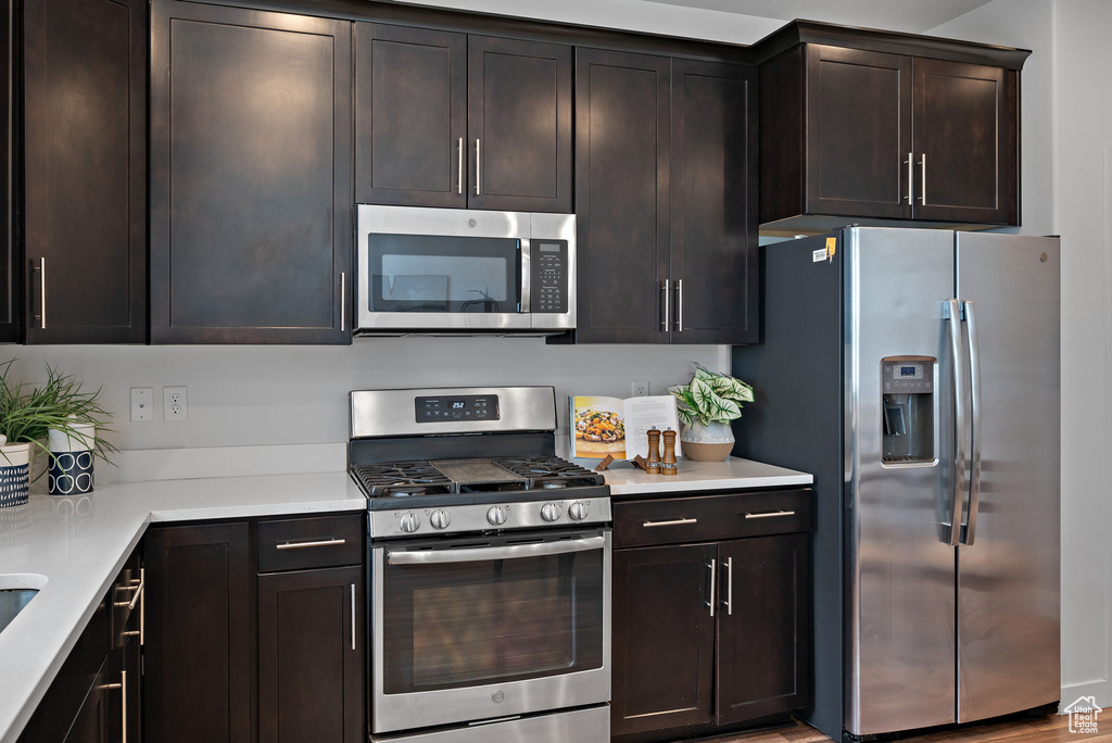 Kitchen with stainless steel appliances, light countertops, and dark brown cabinets