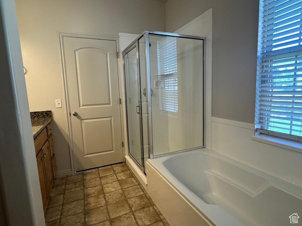 Full bath with vanity, a shower stall, stone finish flooring, and a garden tub